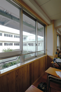 大きなペアガラスと庇が特徴的な教室の窓。左下に突出し窓が見える。