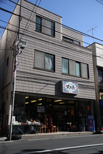 大和市内にある本社の1階には、ガラスの業務とともに長年営業を続けている陶器店が入る。青い機能ガラスが窓にはめ込まれている2階が、中村さんのガラス研究室だ。