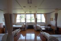 ４人床の病室。南側の壁はほぼ全面が窓になっており、入口側のベッドまで光が届いて明るい。