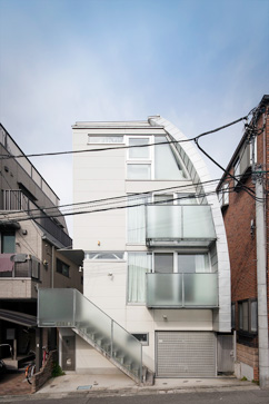 K邸外観。敷地に傾斜があり地階となるフロアは浴室・車庫・オーディオルームにあてられ、1階玄関には階段でアプローチする。