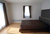 明るめの色調を持つ床に深いブラウンのインテリアと、落ち着いた色調にまとめられた寝室。