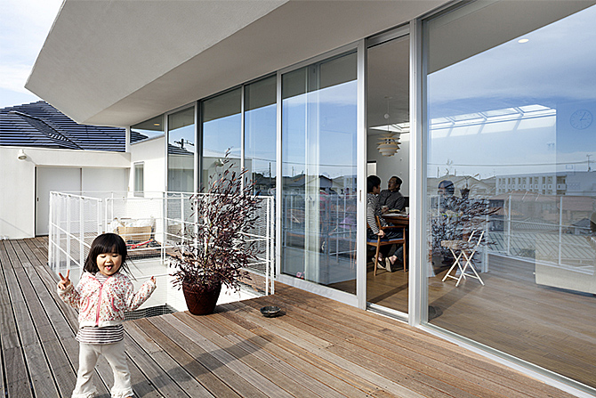 バルコニーの軒の出は2メートルを超え、夏の日中に照りつける日射をシャットアウトするとともに、少々の雨なら窓を開けても室内に降り込まないようになっている。デッキ中央の空隙には、1階から伸びるシマトネリコがやがて顔を出す